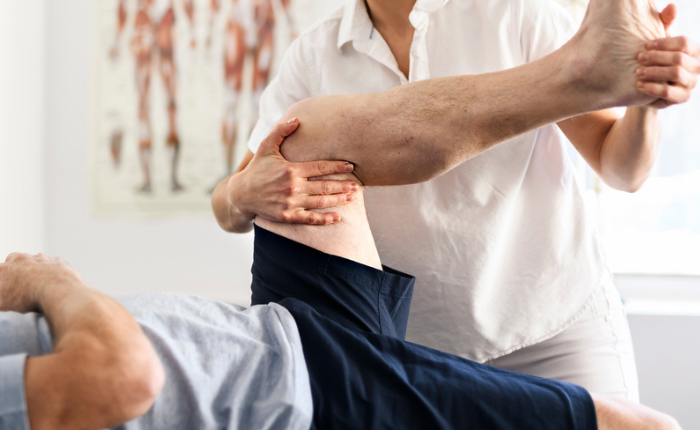 Chiropractor helps patient stretch.